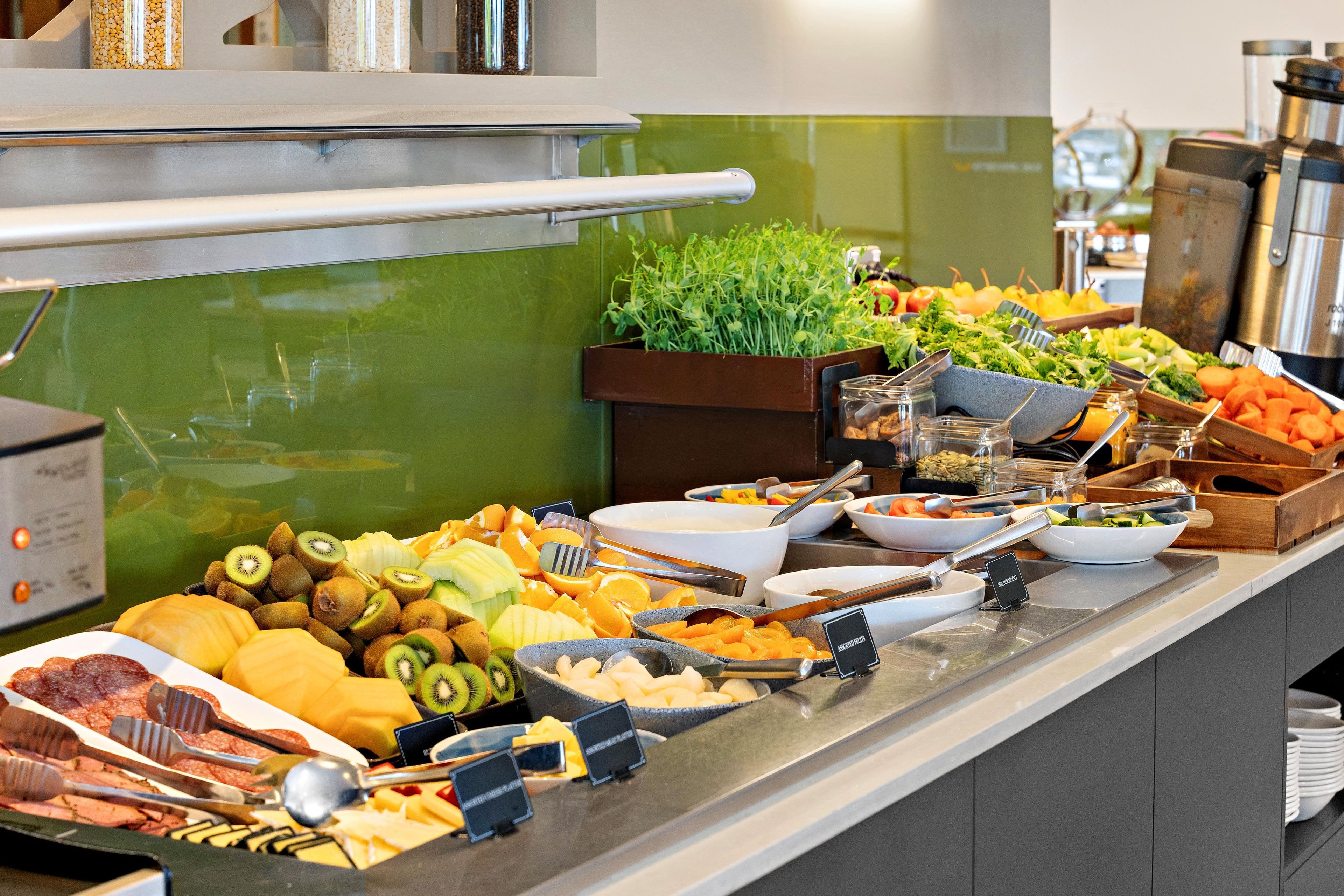 Un bufé con diversos alimentos, entre ellos frutas, verduras y carnes.