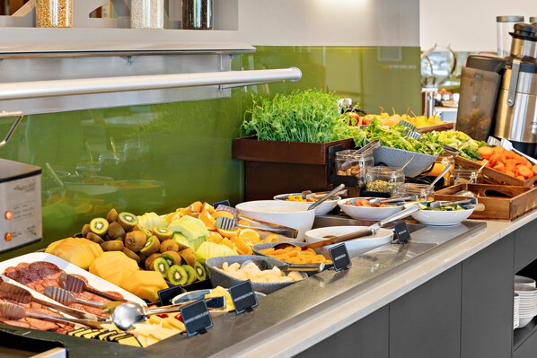 Un bufé con diversos alimentos, entre ellos frutas, verduras y carnes.