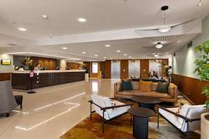 A modern lobby with a reception desk, seating area, and a large ceiling light fixture.