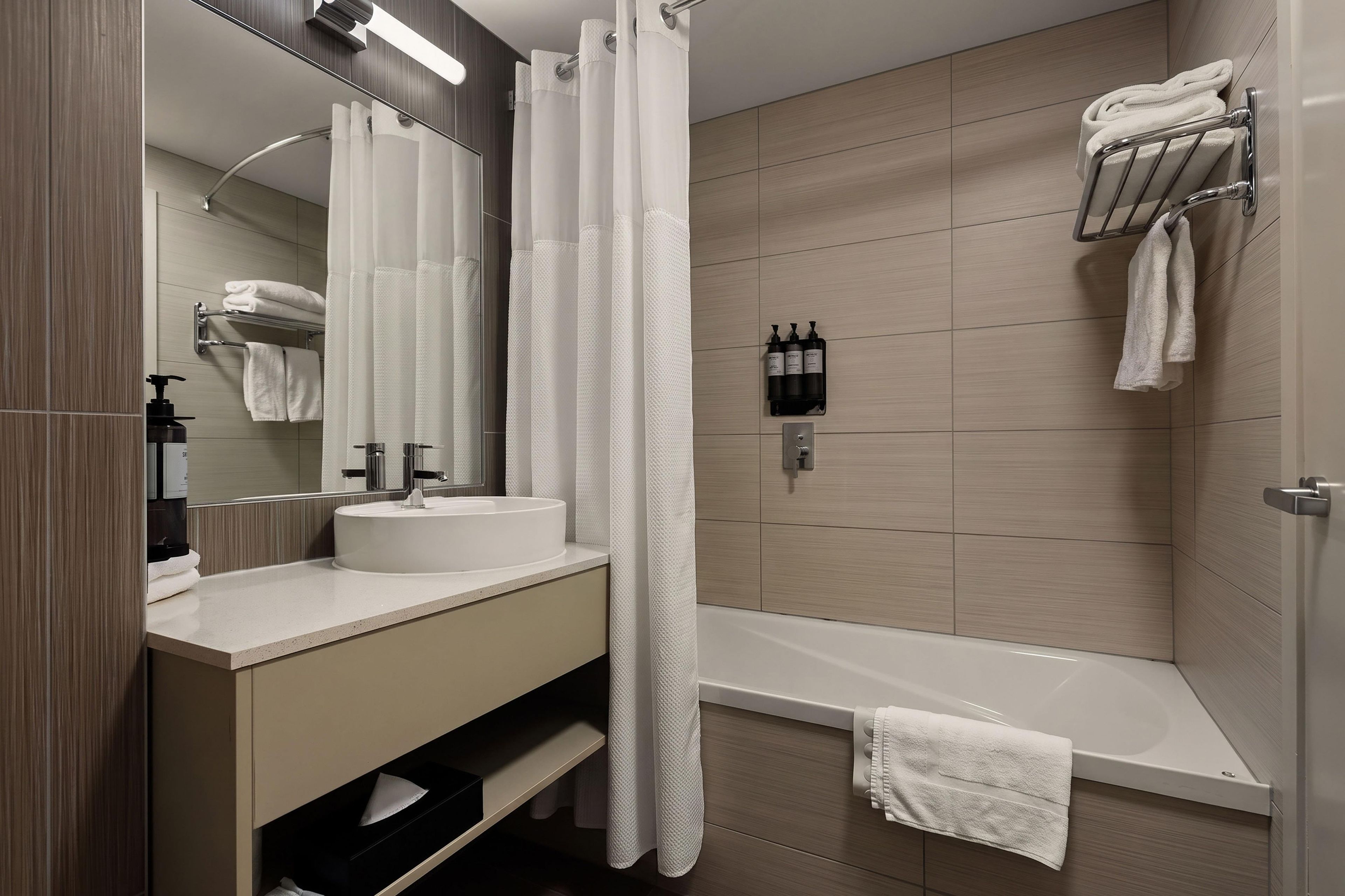 Un baño moderno con bañera, lavamanos, espejo y cortina de ducha.