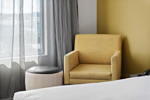 A hotel room with a single armchair, a small ottoman, and a bed. - Sudima Auckland Airport (Auckland)