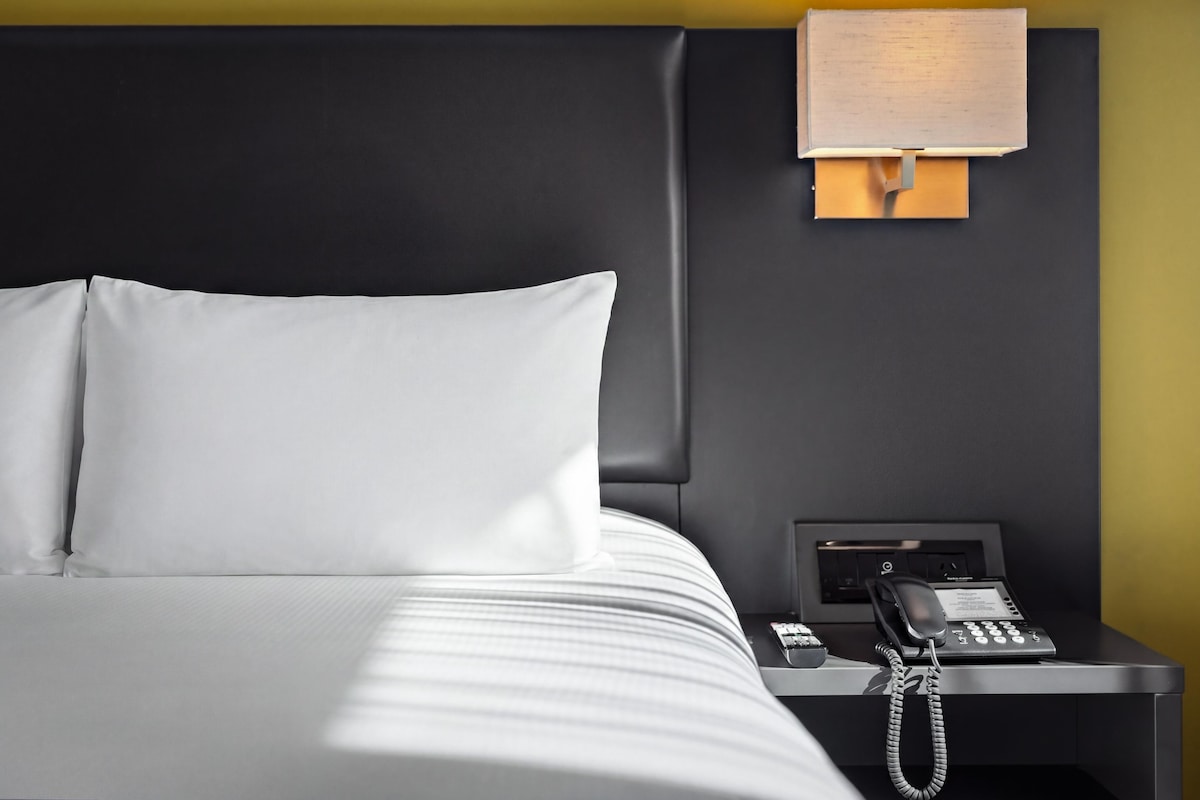A hotel room with a bed, a bedside telephone, and a nightstand.