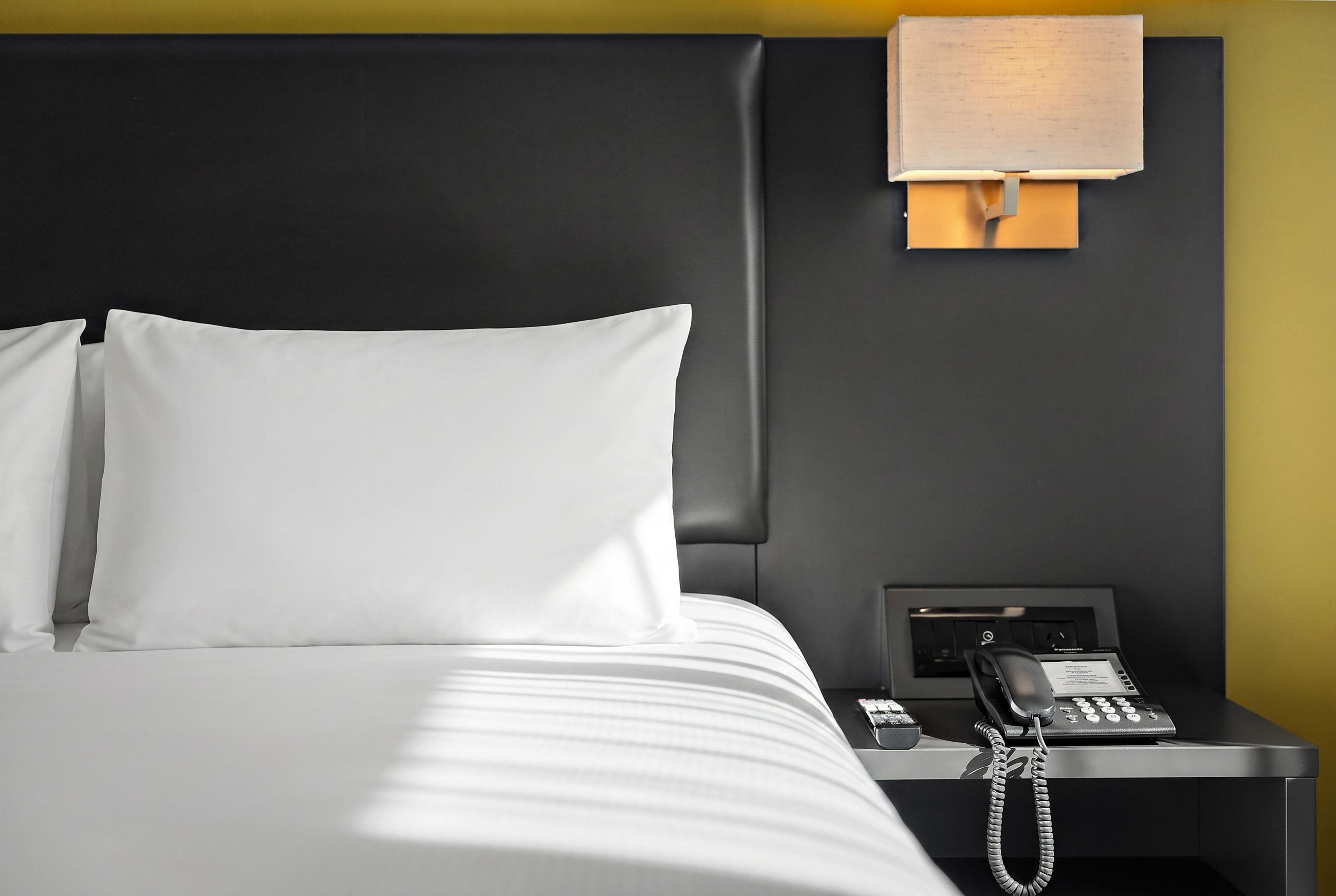 A hotel room with a bed, a nightstand, and a telephone.