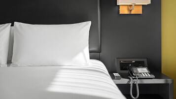 A hotel room with a bed, a nightstand, and a telephone.