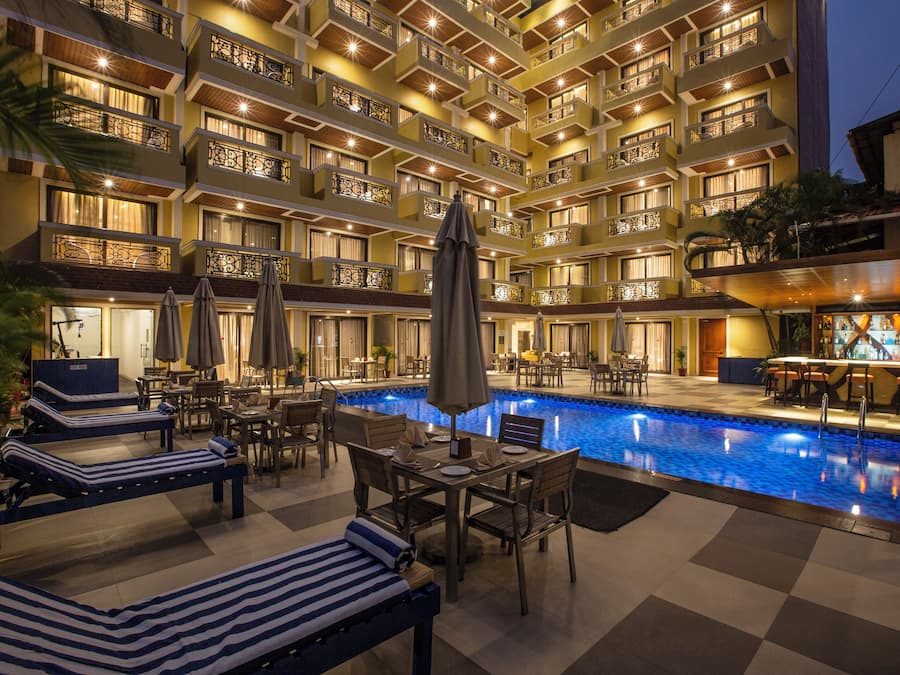 Una piscina al aire libre, sombrillas, sillones reclinables de piscina