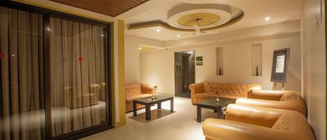 A modern hotel lobby with leather sofas, a glass partition, and a wooden ceiling.