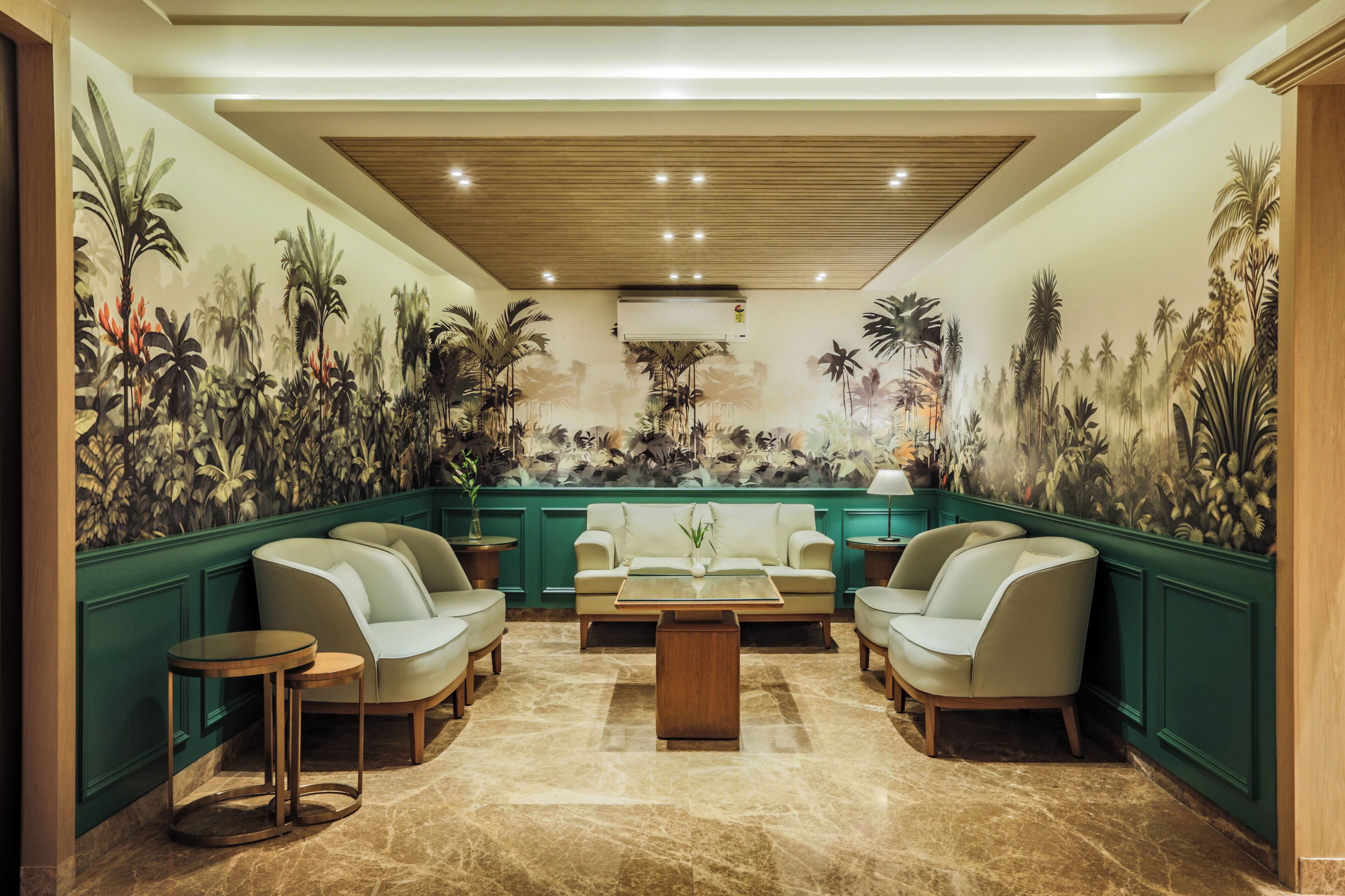 Un hall d’entrée agrémenté d’un mur végétal, d’une fresque représentant des plantes tropicales, d’un canapé, d’une table basse et d’une petite table ronde.