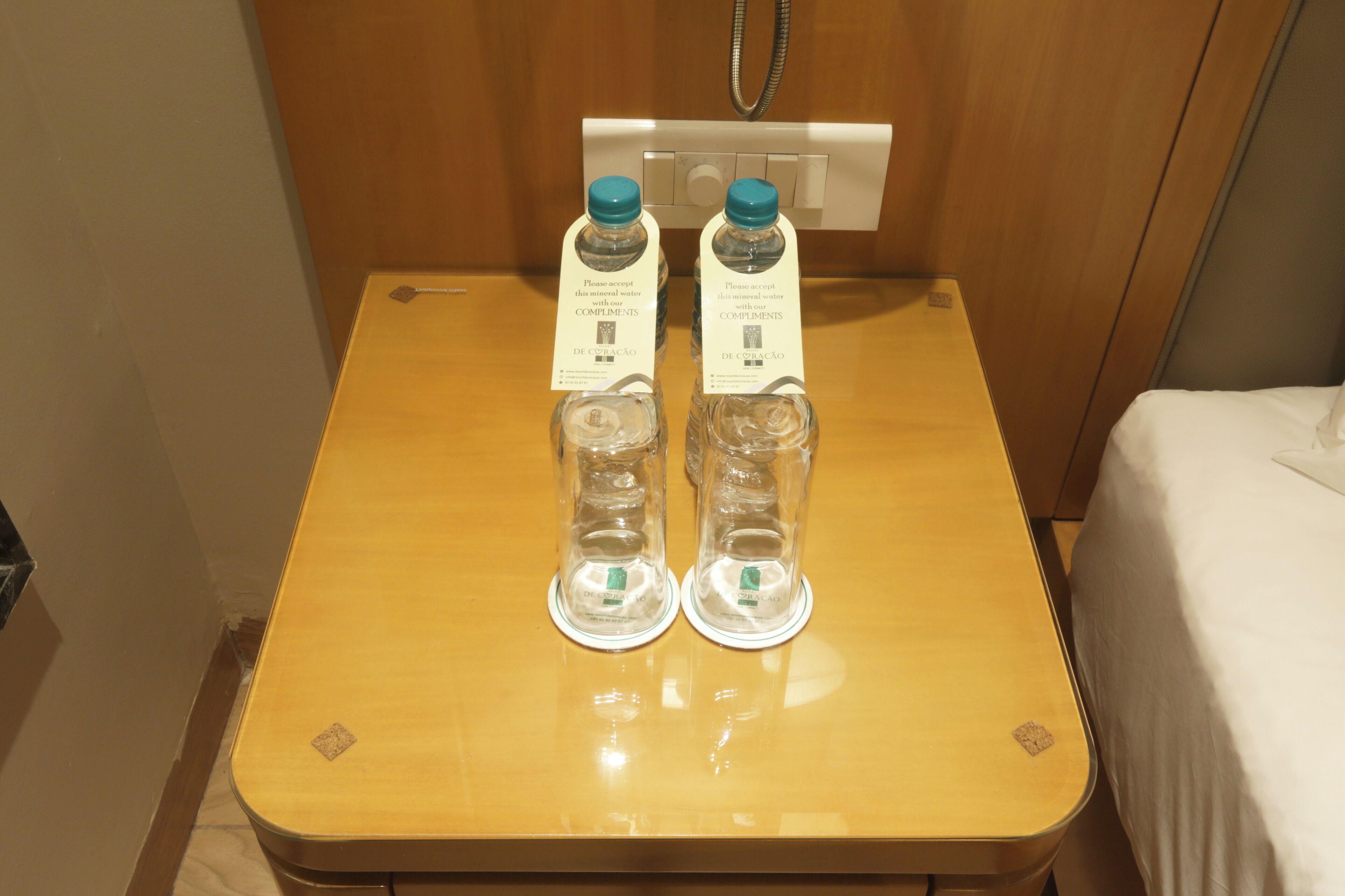 A wooden table with two bottles of water and their labels in a hotel room.