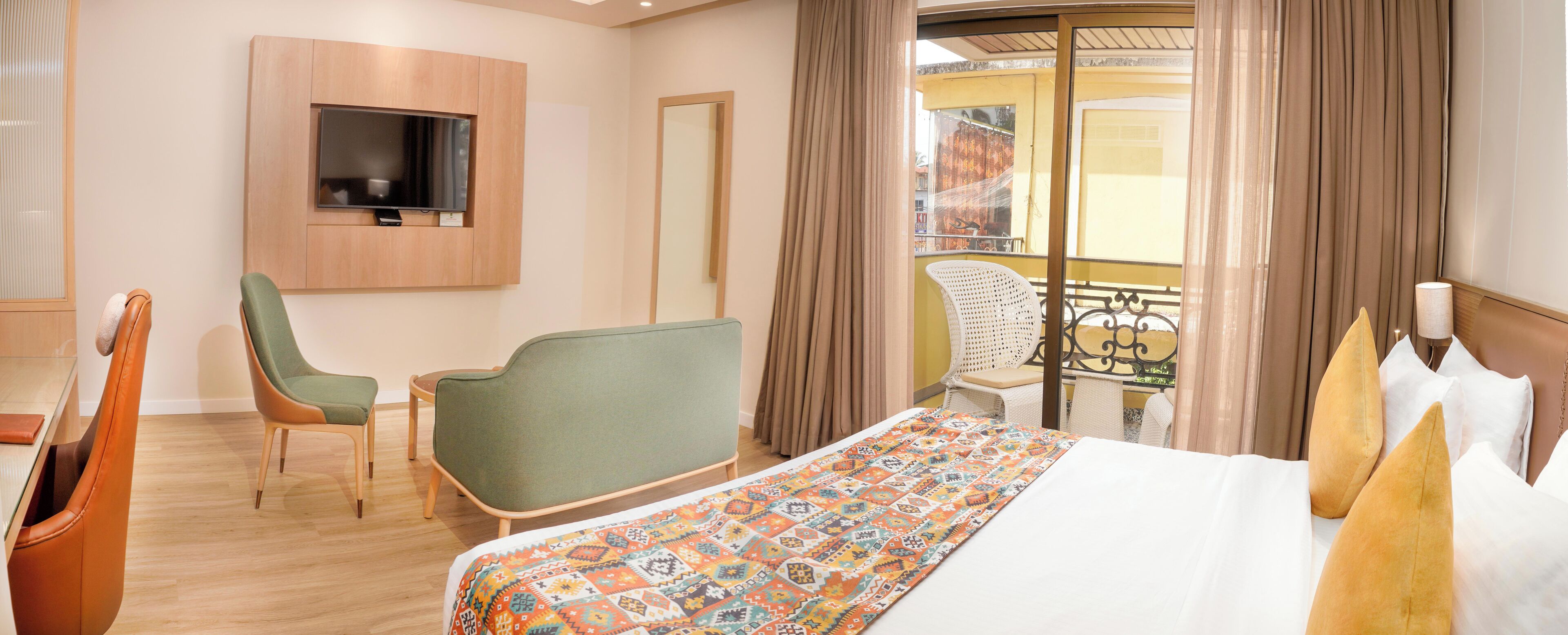 Une chambre d’hôtel comprenant un lit, un téléviseur fixé au mur, un balcon avec une chaise et une table avec une chaise.