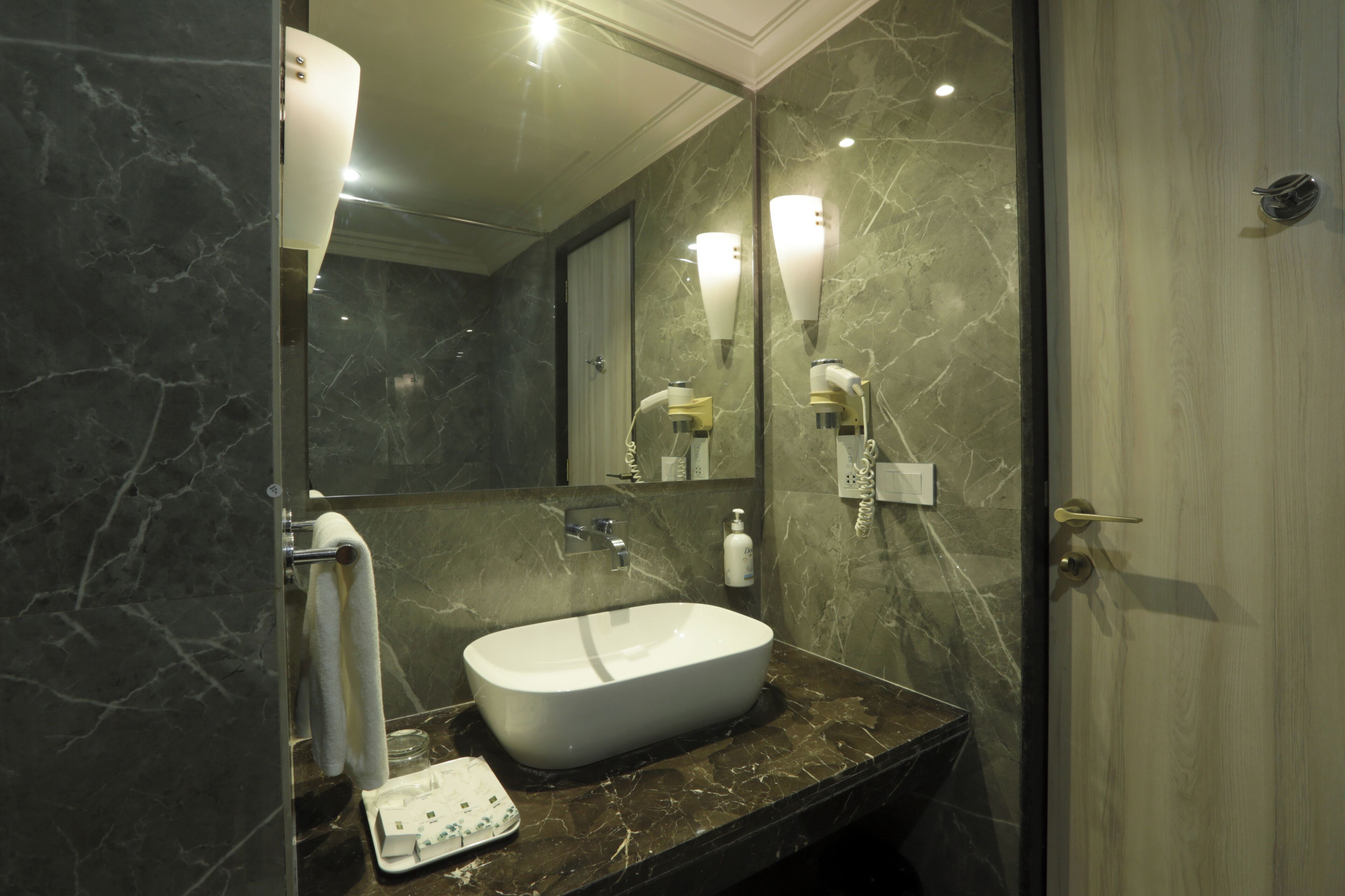Un bagno moderno con lavabo in marmo, portasciuga asciugamani e uno specchio con applique.