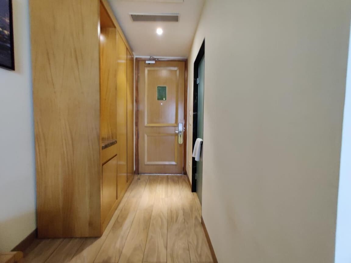 A narrow hallway with wooden flooring and a door at the end.