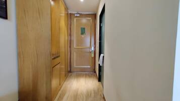 A narrow hallway with wooden flooring and a door at the end.