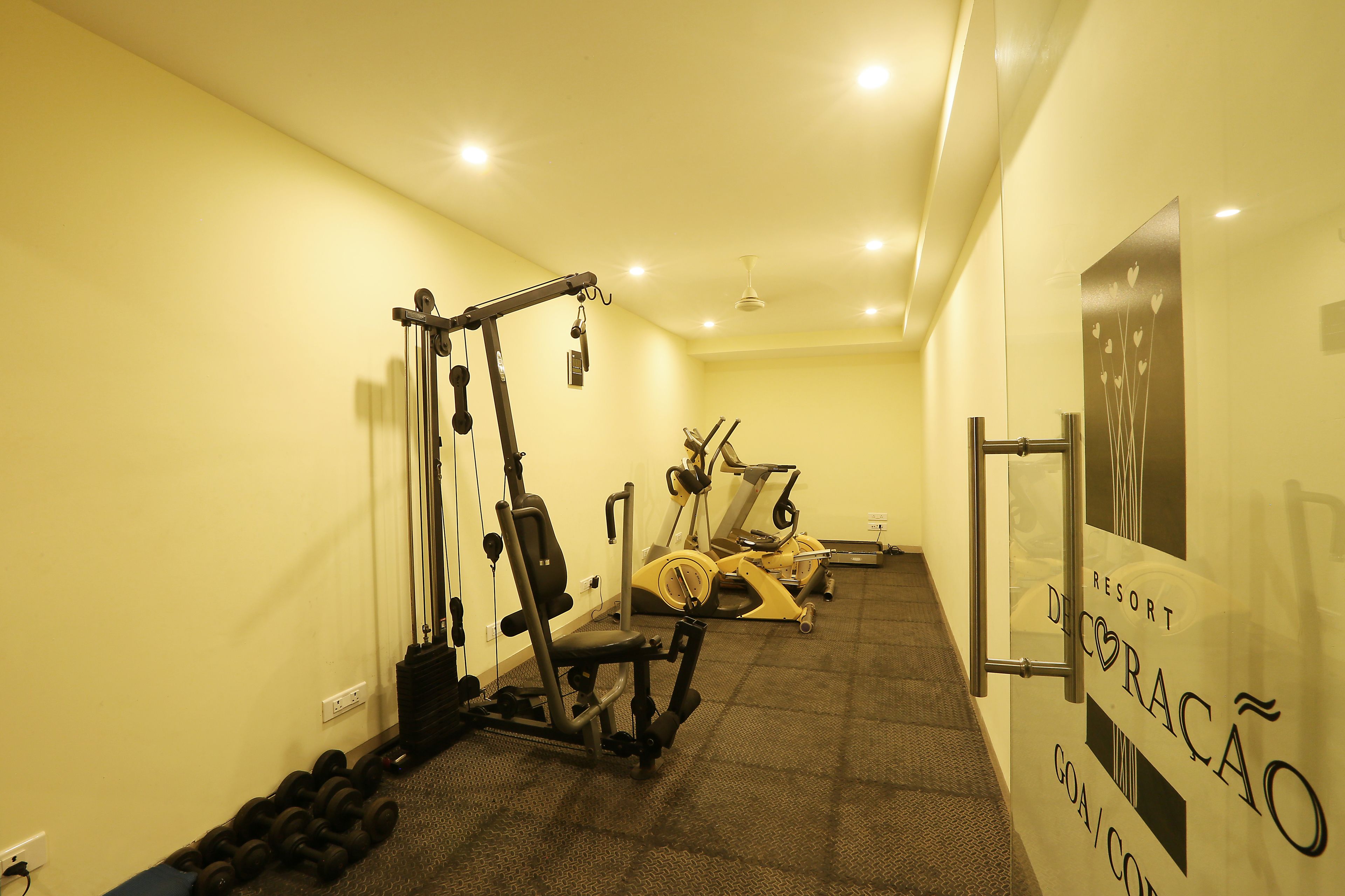 Un gimnasio con equipo de ejercicio, un letrero en la pared y un ventilador de techo.