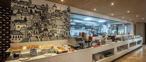 A buffet setup with various food items and a cityscape mural on the wall.