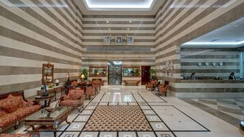 A spacious lobby with striped marble walls, a patterned floor, and traditional furnishings.