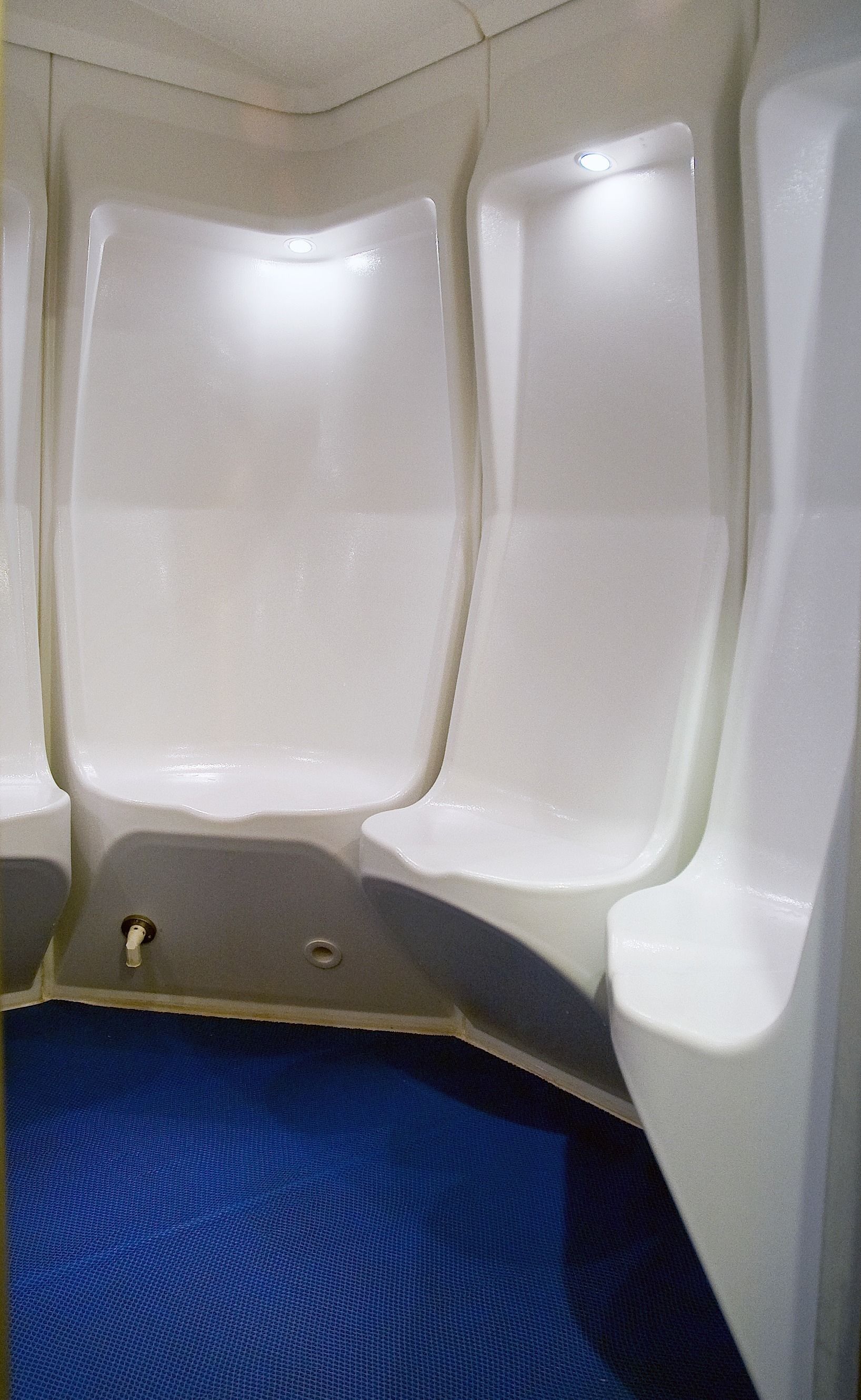 A restroom with two white urinals and a blue floor.