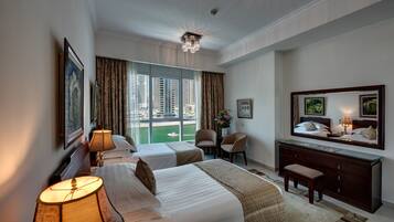 A hotel room with two beds, a desk, a chair, and a large window offering a city view.