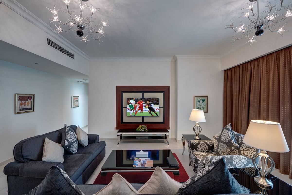 A living room with a TV, sofas, a coffee table, and a lamp.