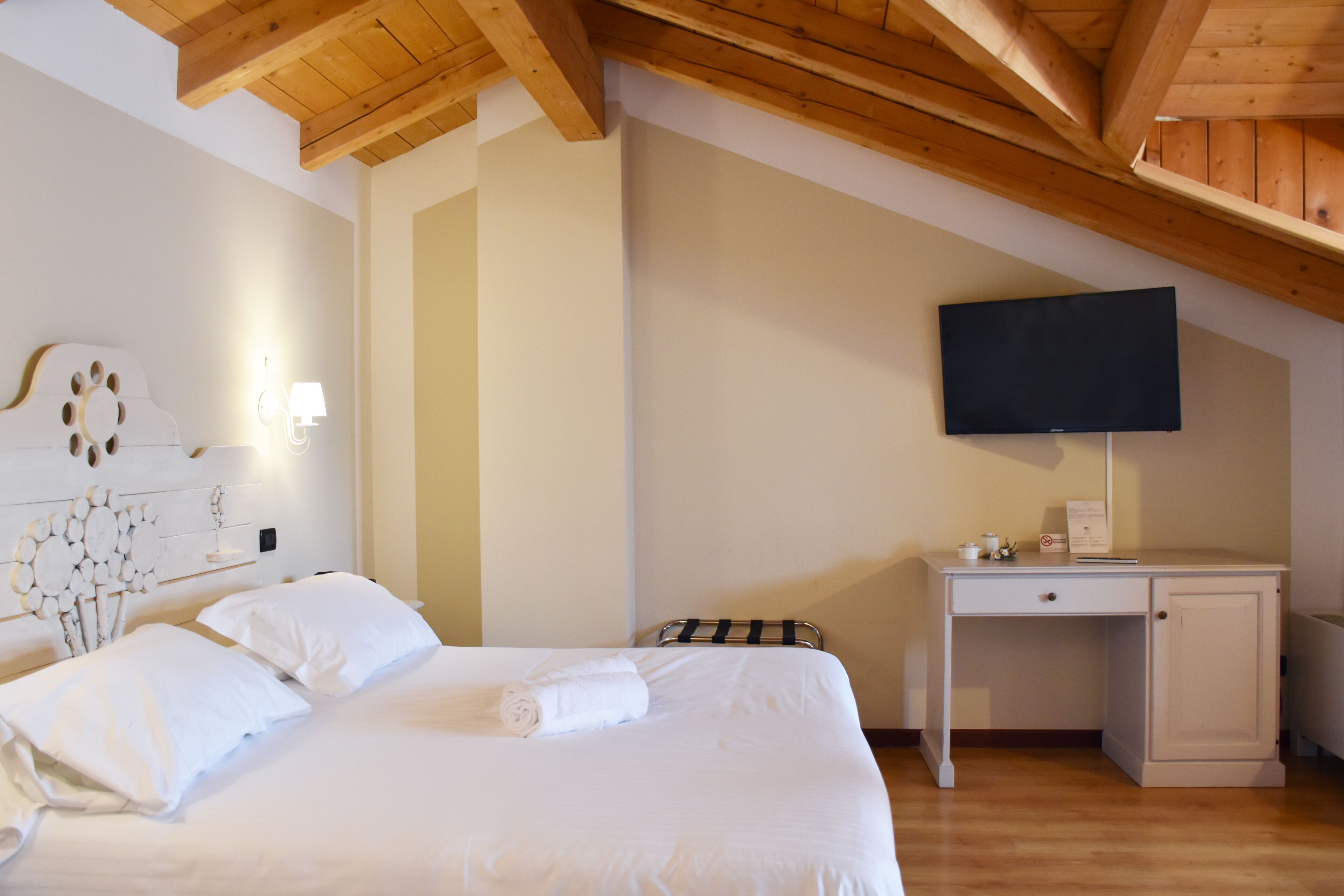 Un dormitorio con cama, escritorio y televisor.