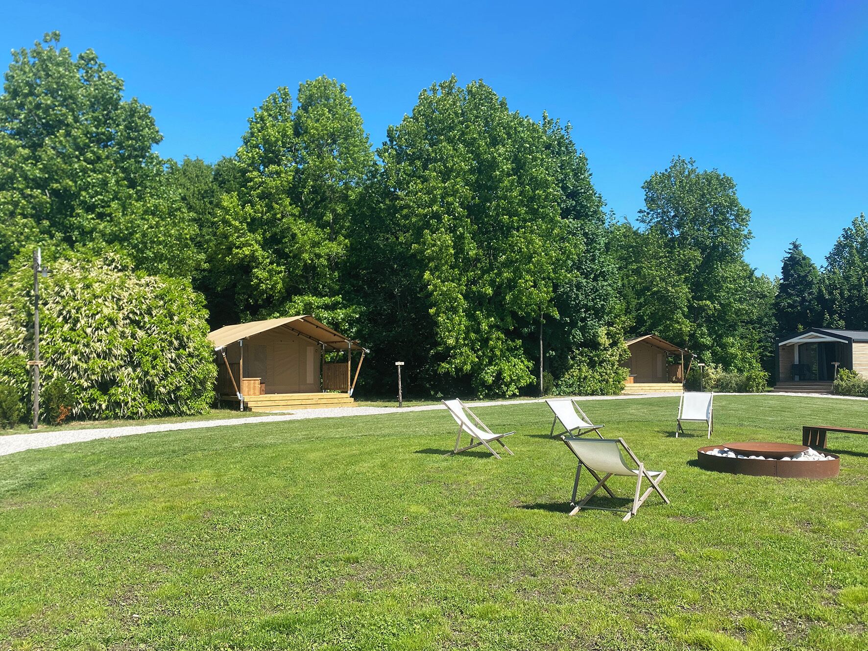 A campsite with a covered seating area, a fire pit, and several lawn chairs.