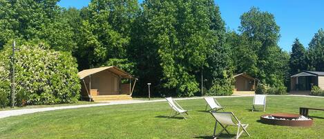 A campsite with a covered seating area, a fire pit, and several lawn chairs.