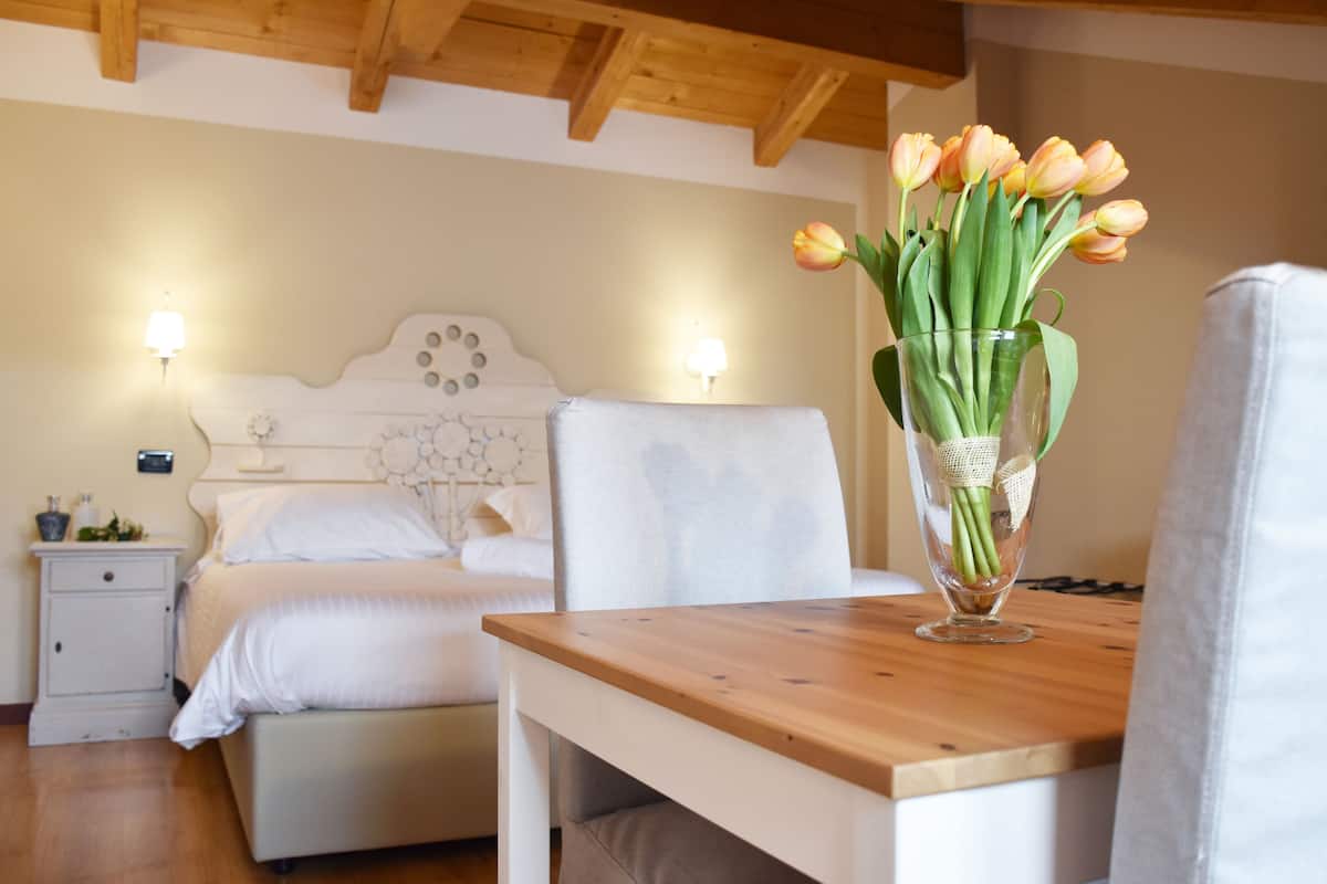 Une chambre à coucher avec un lit en bois, des tables de chevet et un vase de tulipes posé sur une table en bois.