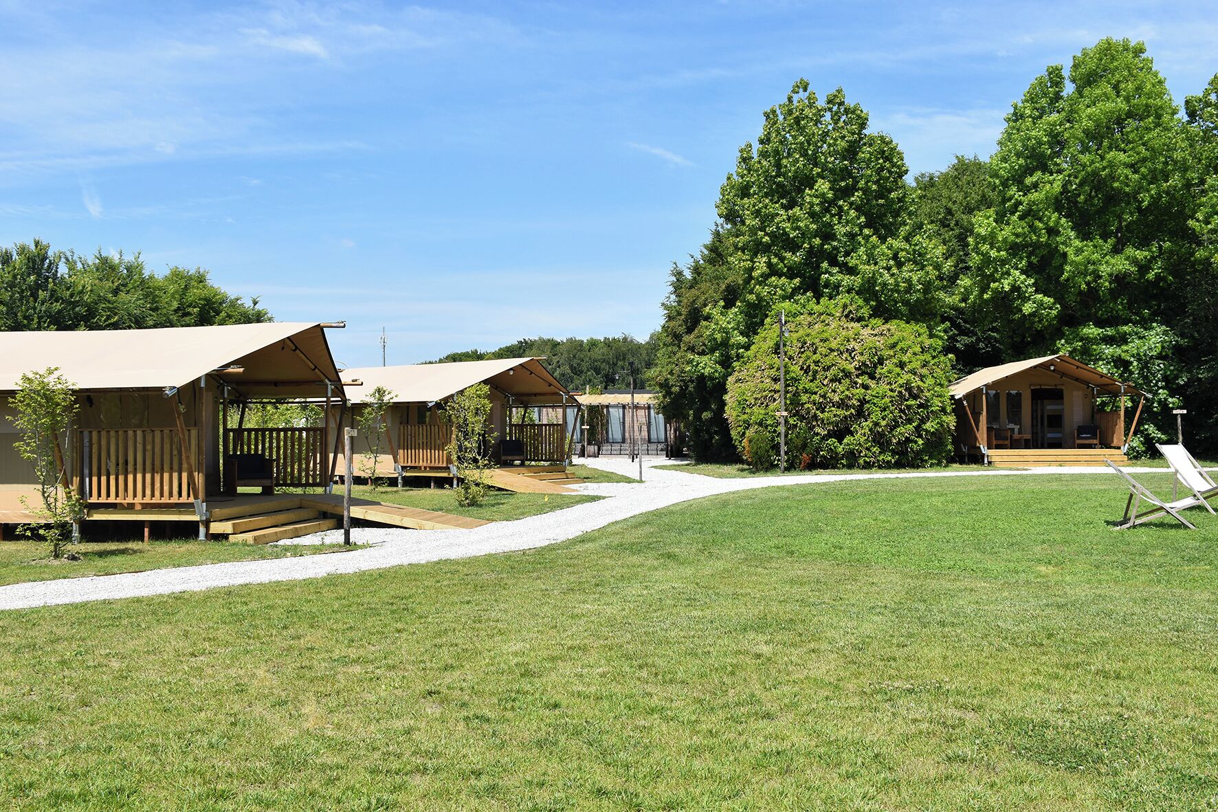 A campsite with several wooden cabins, each with a porch and a bench.