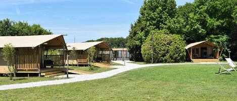 A campsite with several wooden cabins, each with a porch and a bench.