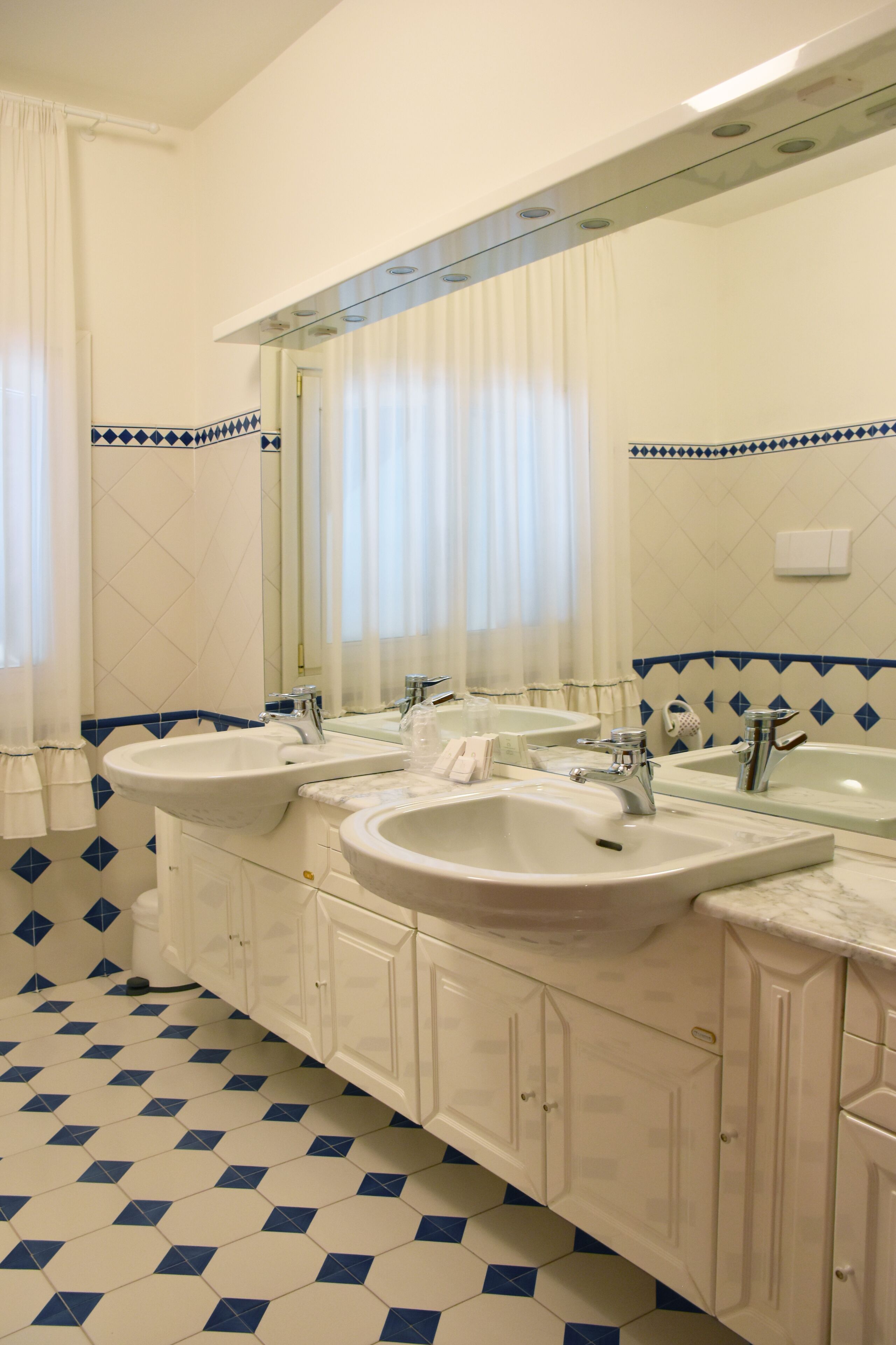 Ein Badezimmer mit zwei Waschbecken, einem großen Spiegel und einem gefliesten Boden.