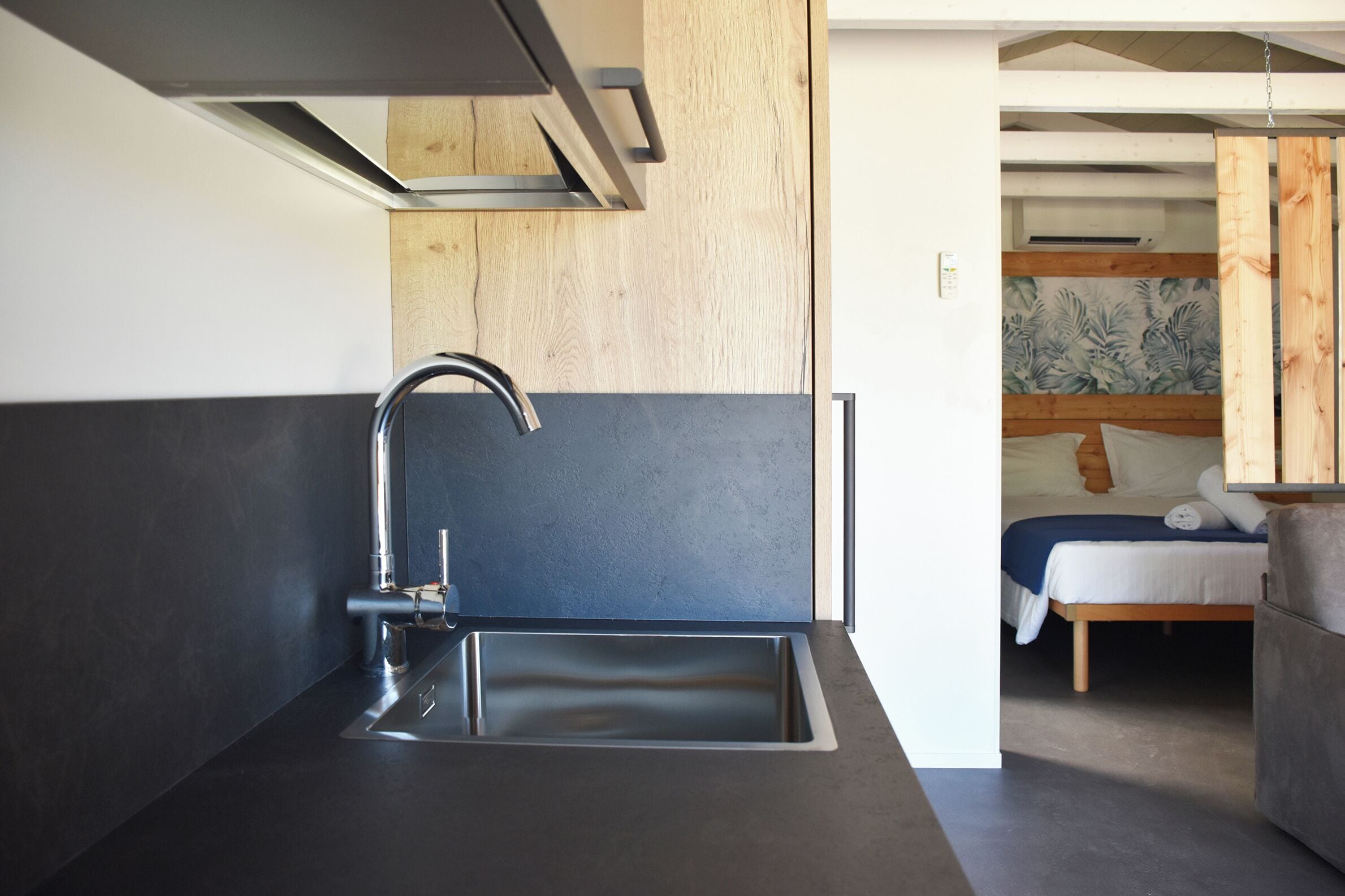 A modern kitchen with a stainless steel sink and a wooden accent wall.