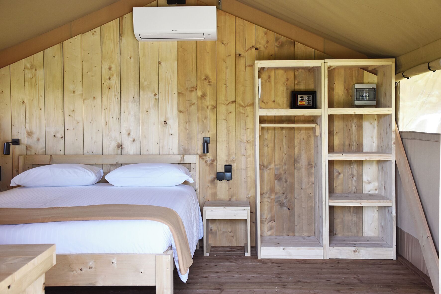 Une pièce en bois comprenant un lit, une petite table, une étagère et un radiateur fixé au mur.