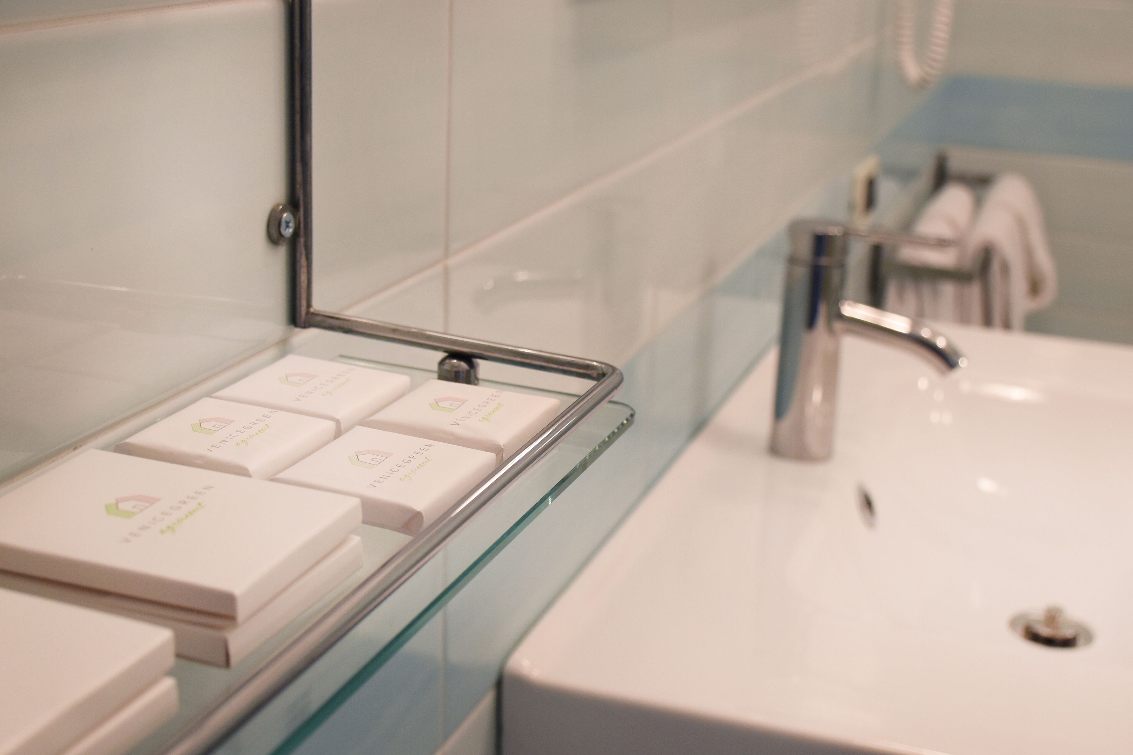 A bathroom with a glass shelf holding several toiletries.
