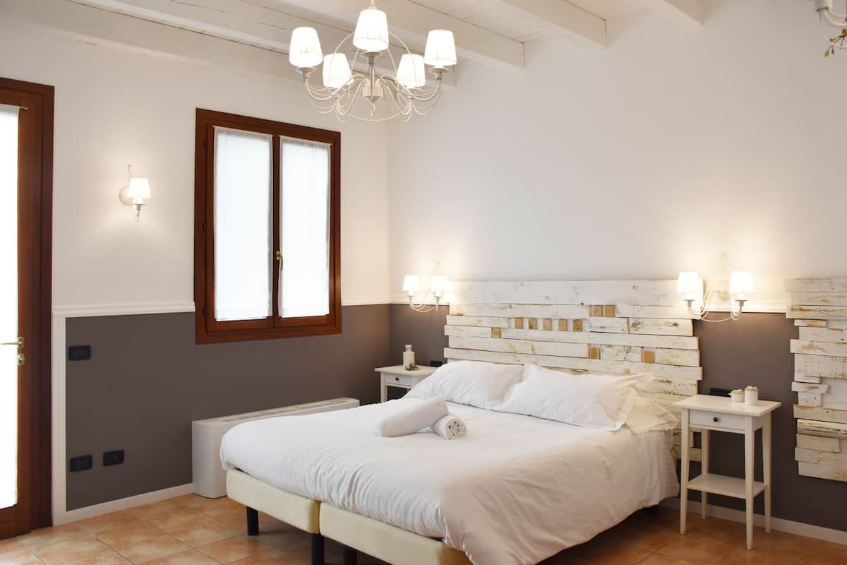 Une chambre à coucher avec un lit, des tables de chevet, un lustre et un luminaire fixé au mur.
