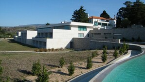 A modern building with a pool, surrounded by a landscaped area with small trees. - INATEL Vila Ruiva Hotel (Fornos de Algodres)