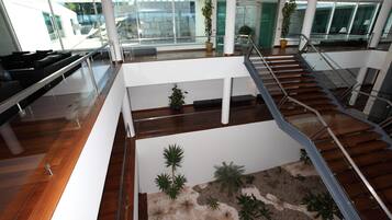 A spacious lobby with a central seating area, a staircase, and a view of the outside.