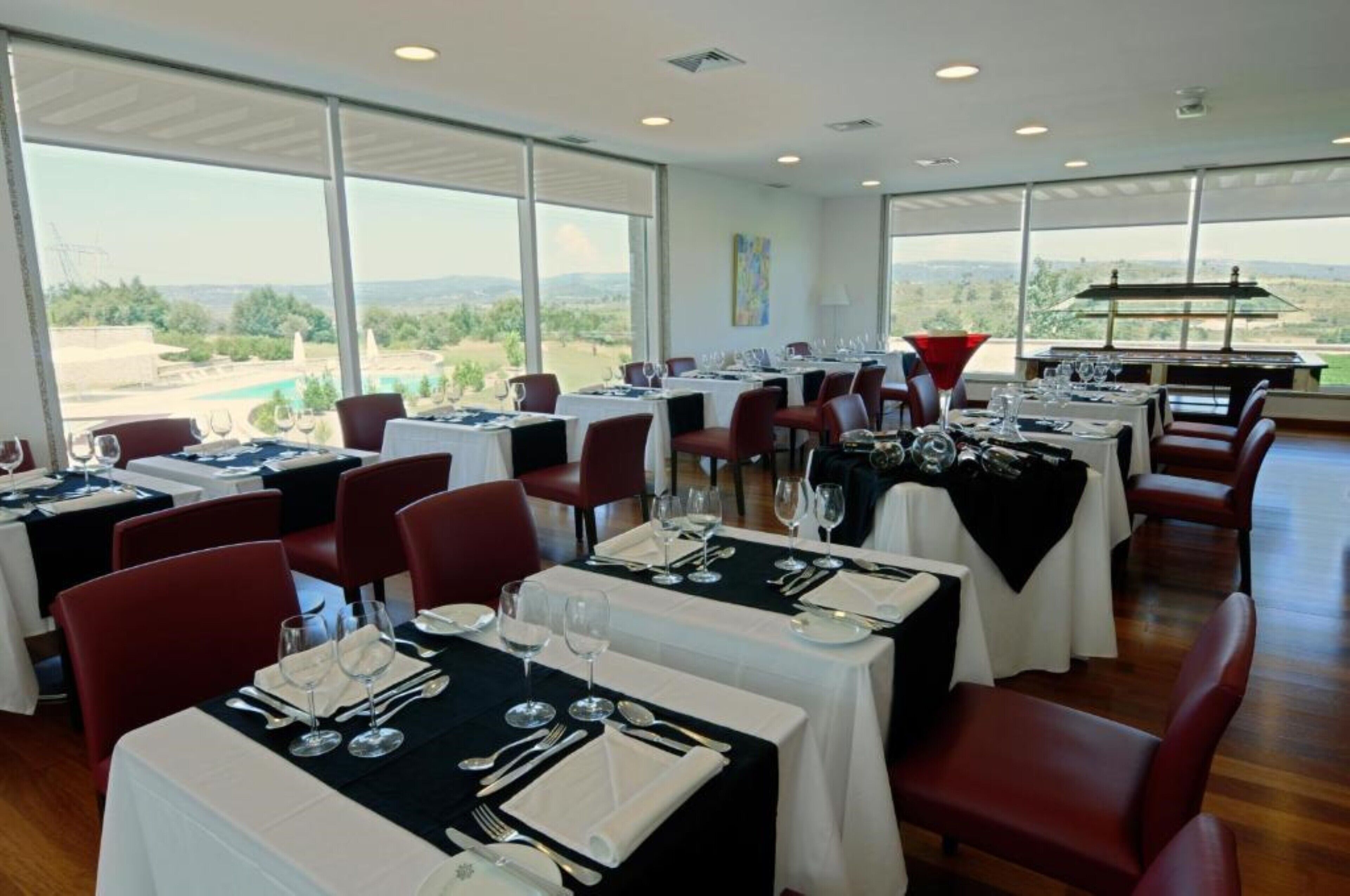 Un restaurante con varias mesas dispuestas para comer, amplias ventanas que ofrecen vistas del paisaje y un diseño de interiores moderno.