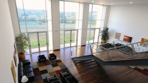 A spacious lobby with a large window view, a staircase, and a seating area with a patterned rug. - INATEL Vila Ruiva Hotel (Fornos de Algodres)