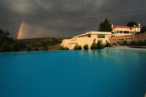 Une piscine avec vue sur un immeuble et un arc-en-ciel en arrière-plan.