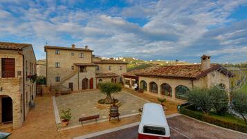 A courtyard with stone buildings, a red and white van, and a clear sky.