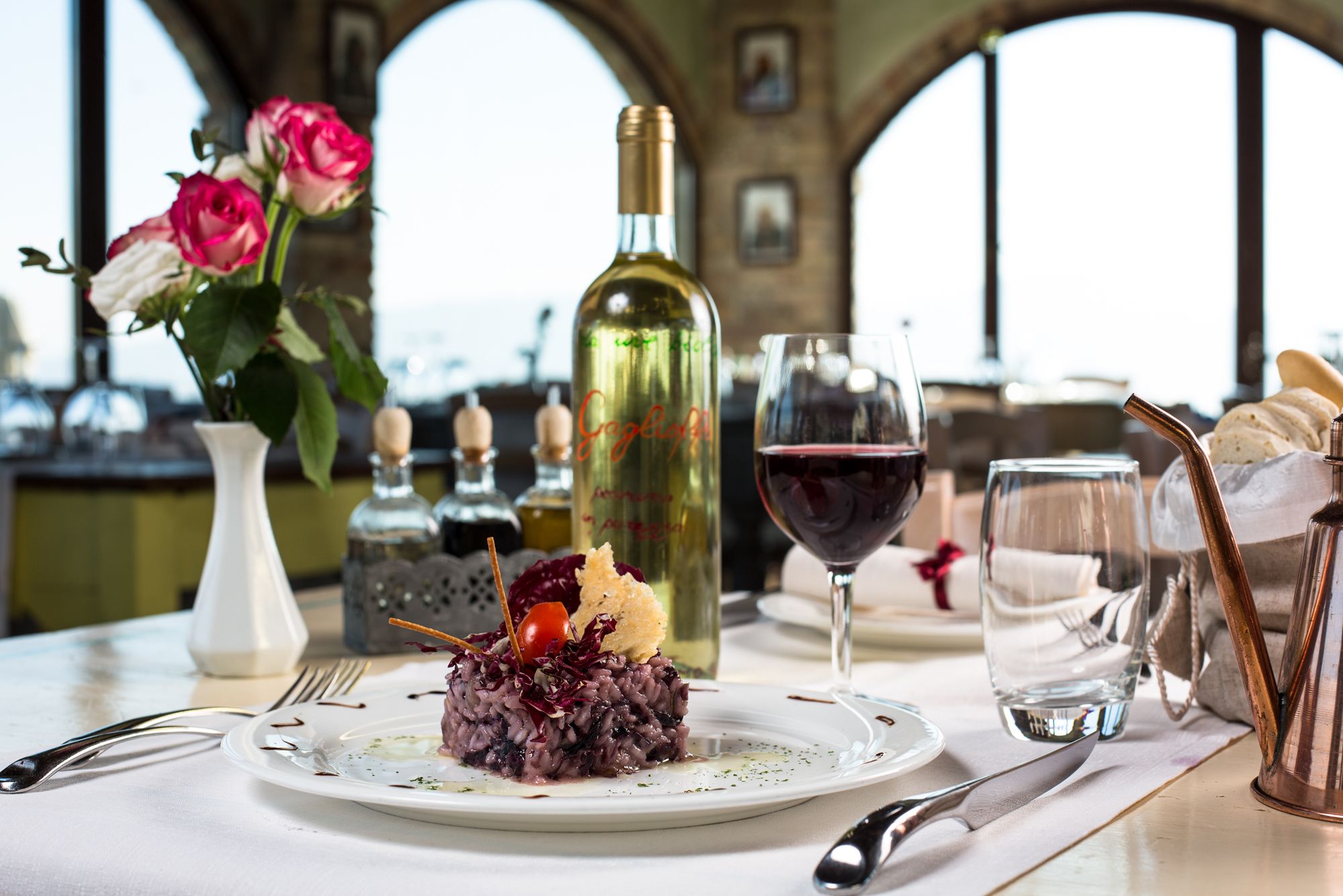 Una mesa de comedor con un plato de comida, una copa de vino y una botella.