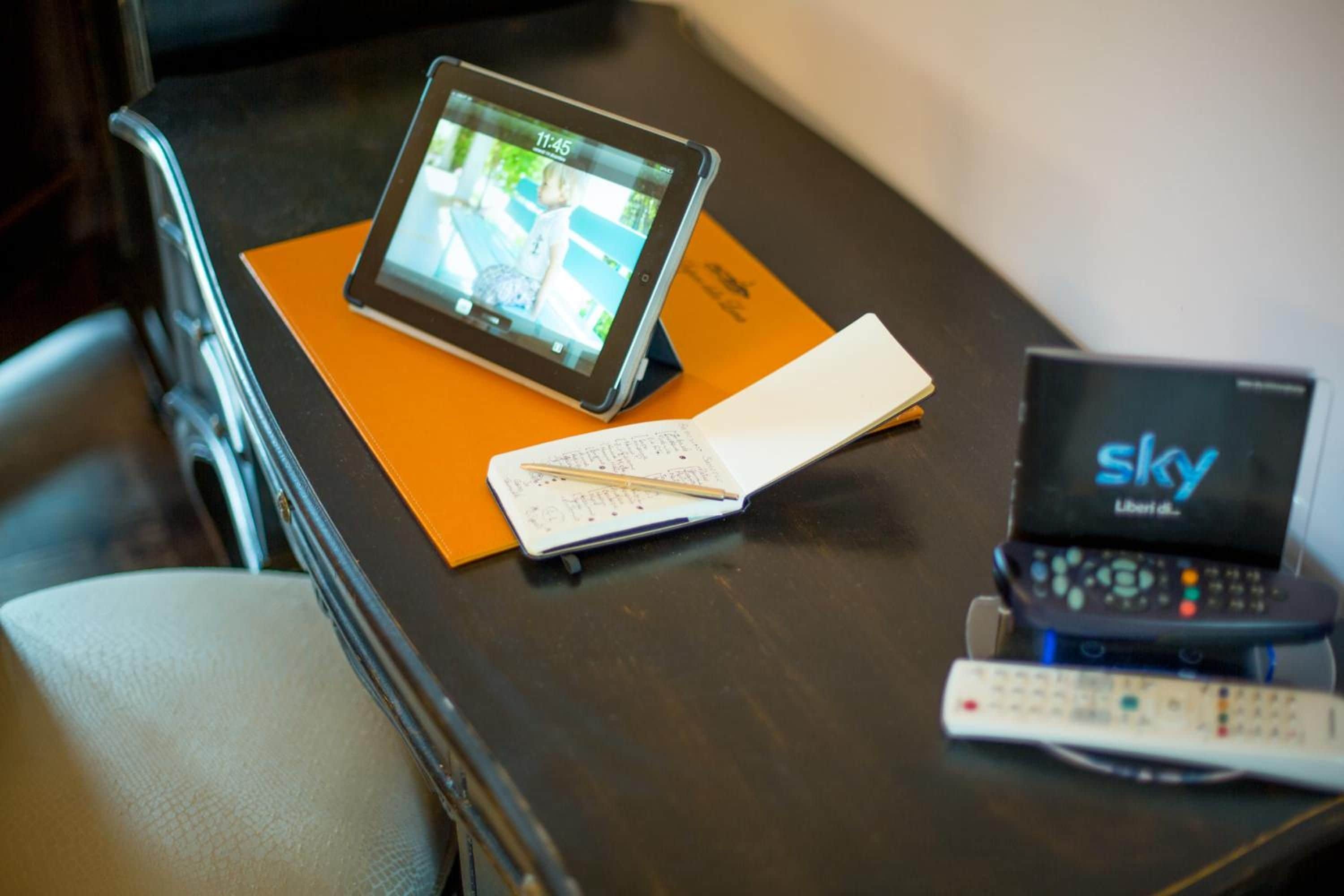 A tablet on a tray, a remote control, and a notebook on a table.