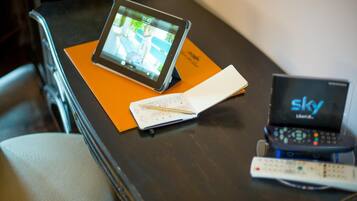 A tablet on a tray, a remote control, and a notebook on a table.