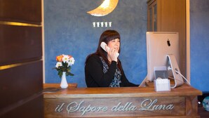 A reception desk with a wooden counter, a computer, and a vase with flowers. The wall behind has a crescent moon design and the number '11111'. -  IL SAPORE DELLA LUNA SRL (Monteprandone)