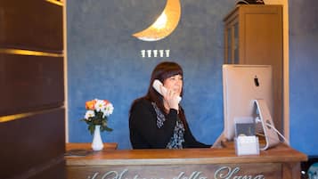 A reception desk with a wooden counter, a computer, and a vase with flowers. The wall behind has a crescent moon design and the number '11111'.
