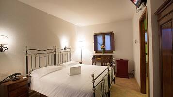 Una camera da letto con un letto, una scrivania, una sedia, una lampada, una televisione e una porta.
