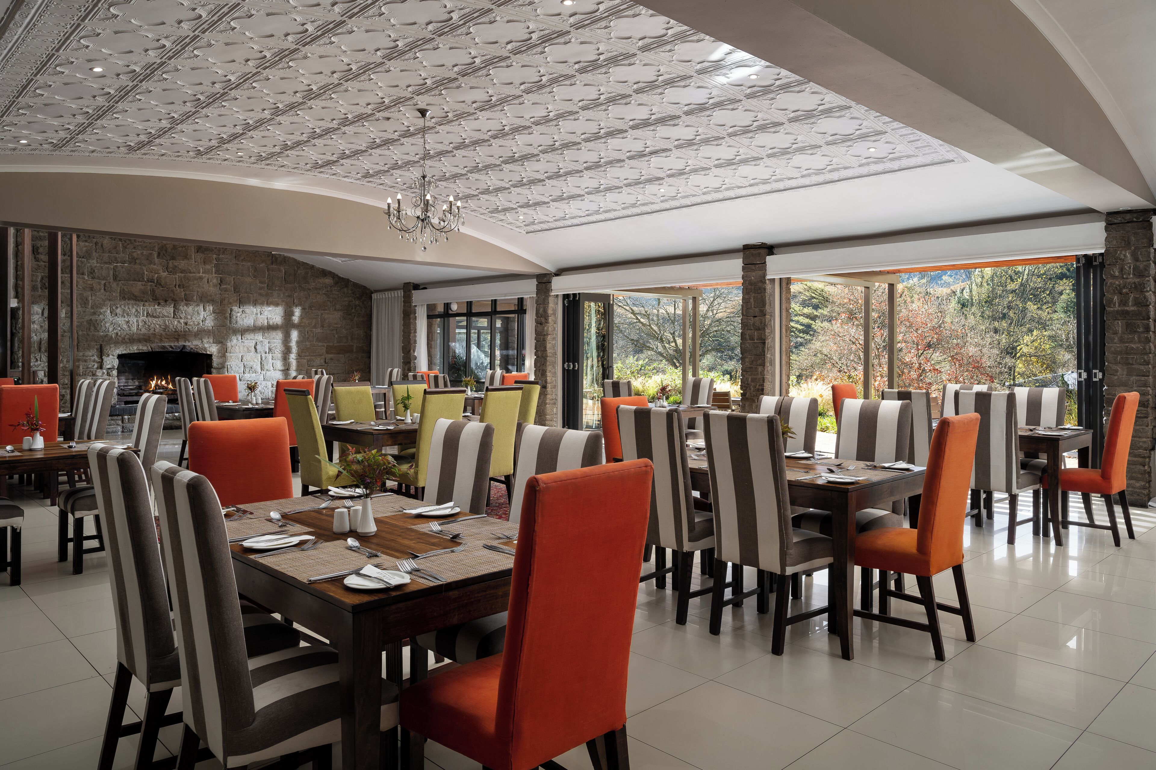 Un comedor espacioso con techos altos, chimenea y grandes ventanales que ofrecen vistas al exterior.