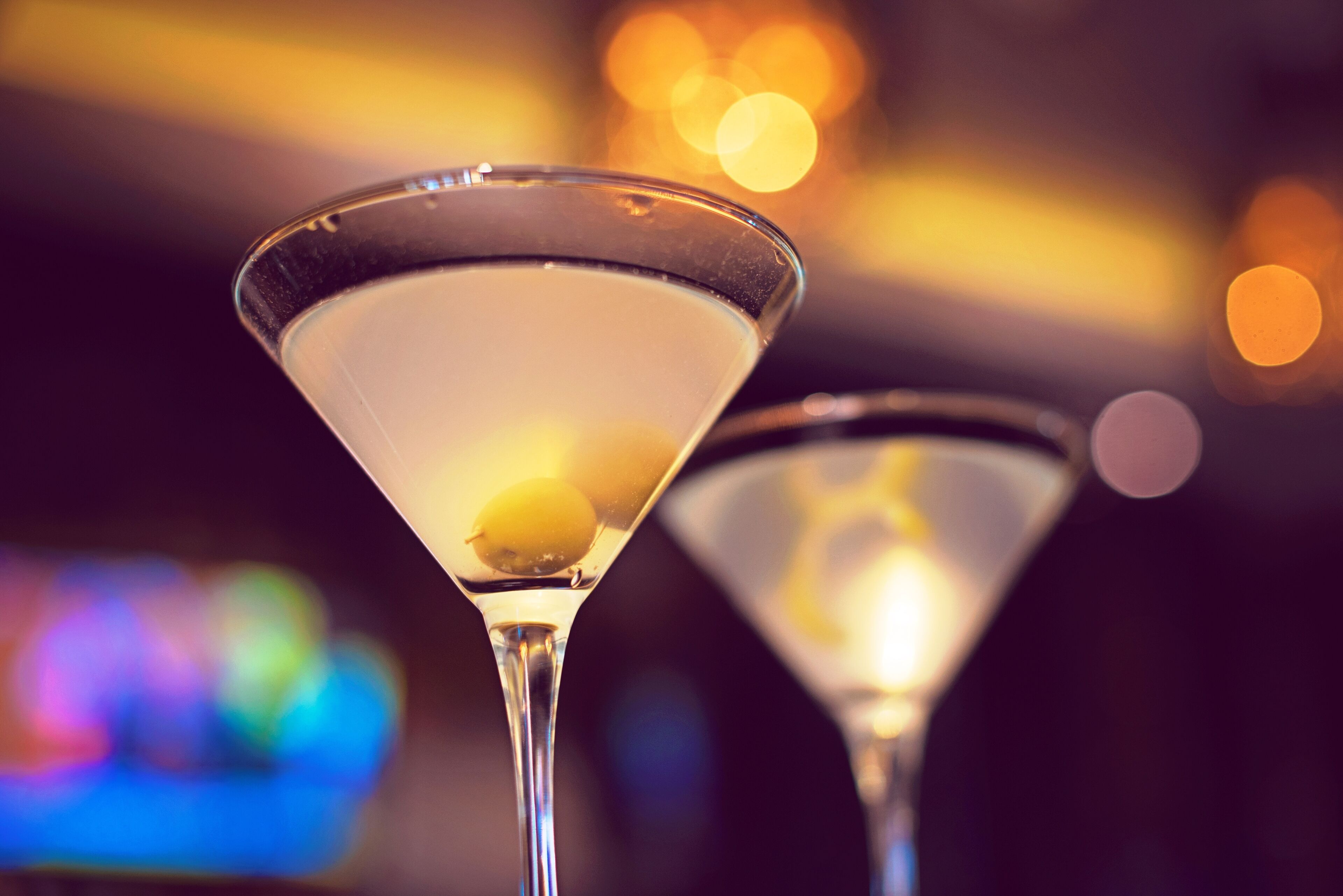 Two martini glasses with a lemon slice, set against a blurred background with bokeh lights.