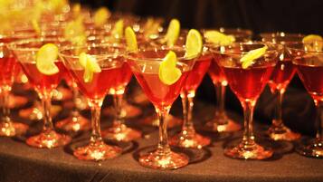 A row of martini glasses filled with a red beverage, garnished with lemon slices, on a table.