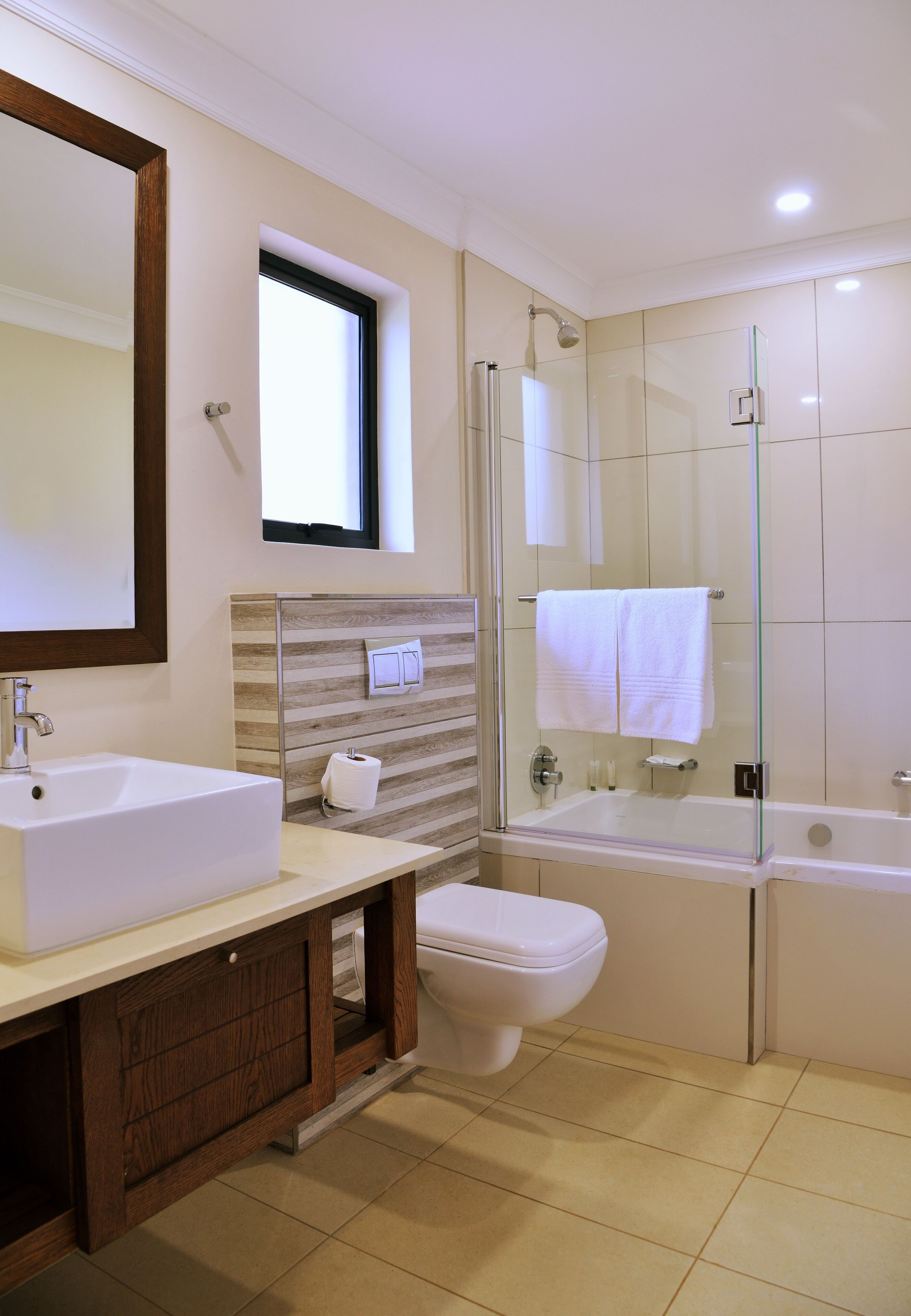 A modern bathroom with a large sink, toilet, and glass-enclosed shower.