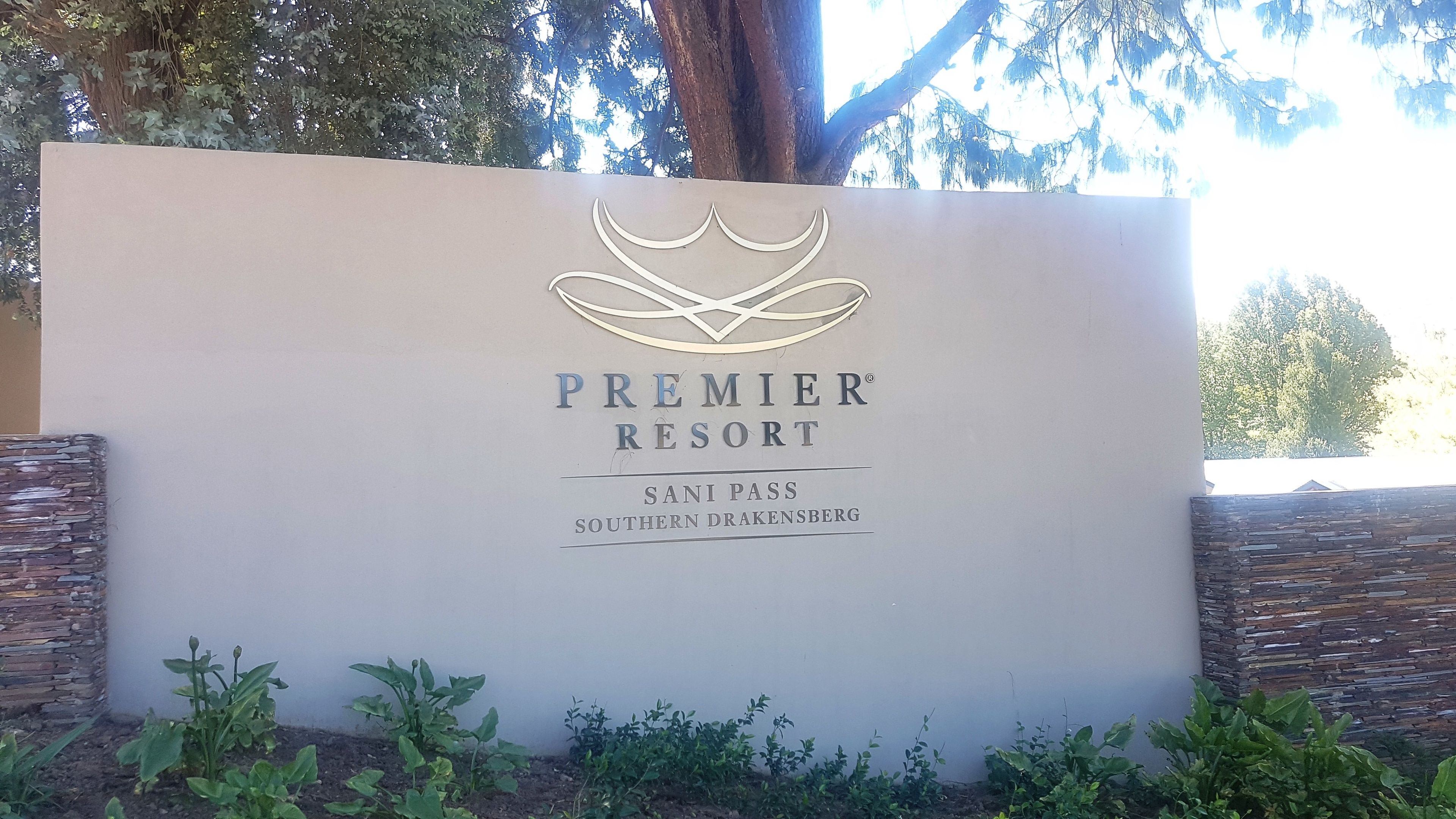 A sign for Premier Resort with a logo, name, and location.